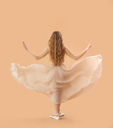 Young ballerina dancing on beige background, back viewの写真素材