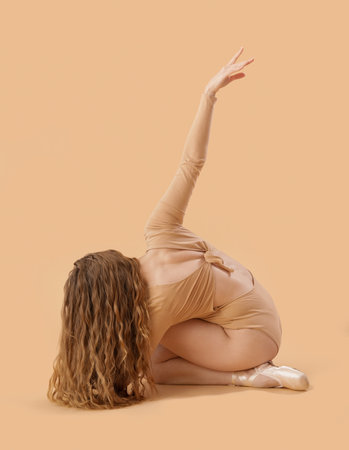 Young ballerina dancing on beige backgroundの写真素材