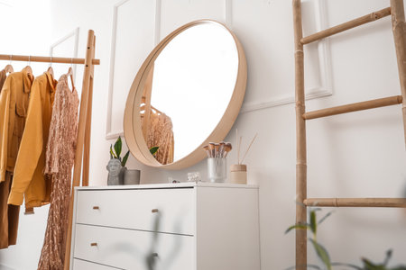 Interior of stylish dressing room with mirror, drawers and clothesの写真素材