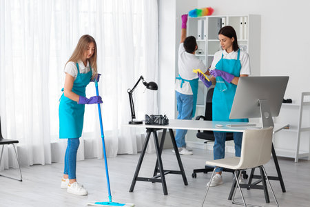 Young janitor cleaning in modern officeの写真素材