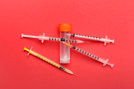 Medical syringes with bottle on red backgroundの写真素材