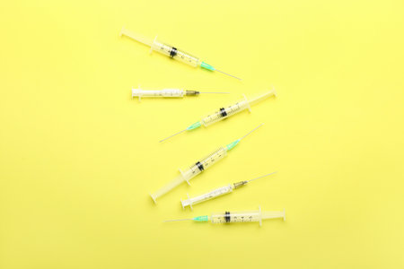 Empty medical syringes on yellow backgroundの写真素材