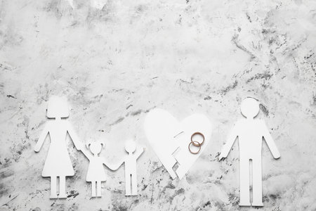 Figures of family with broken heart and rings on light backgroundの写真素材