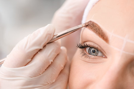 Young woman undergoing eyebrow correction procedure in beauty salon, closeupの写真素材