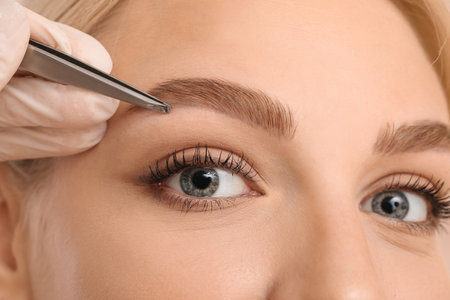 Young woman undergoing eyebrow correction procedure, closeupの写真素材