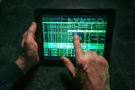 Hands of hacker with tablet computer on dark background