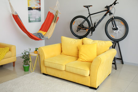 Stylish sofa with hammock and bicycle in the interior of the roomの写真素材