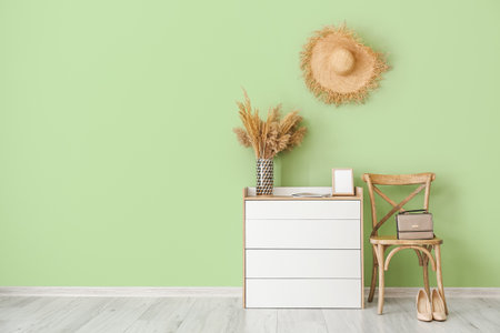 Modern chest of drawers and chair near color wall in roomの写真素材
