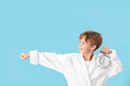 Little boy with alarm clock on color backgroundの写真素材