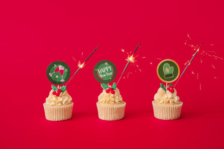 Tasty Christmas cupcakes with sparkler on color backgroundの写真素材