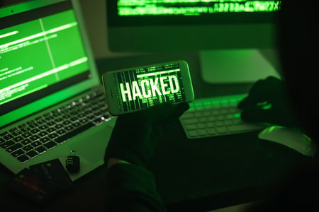 Hacker with mobile phone using computers in dark room