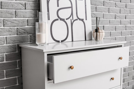 Modern chest of drawers with decor and picture on brick backgroundの写真素材
