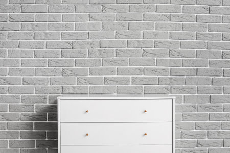 Modern chest of drawers on brick backgroundの写真素材