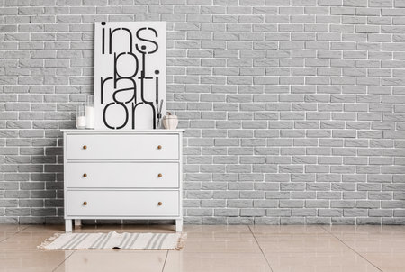 Modern chest of drawers with decor and picture near brick wall in roomの写真素材