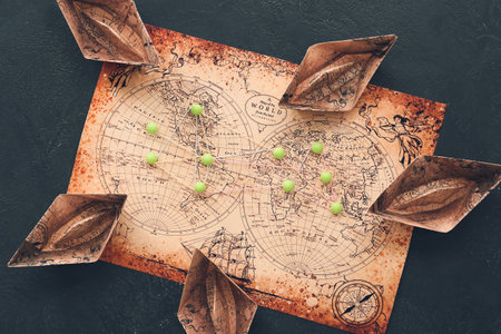 Paper boats, world map and pins on dark backgroundの写真素材
