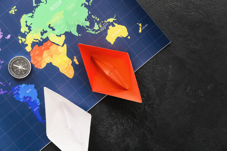 Paper boats, compass and world map on dark backgroundの写真素材
