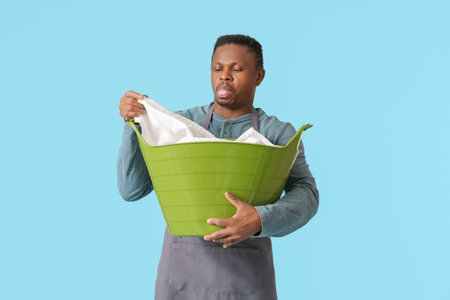 Displeased African-American man with laundry on color backgroundの写真素材