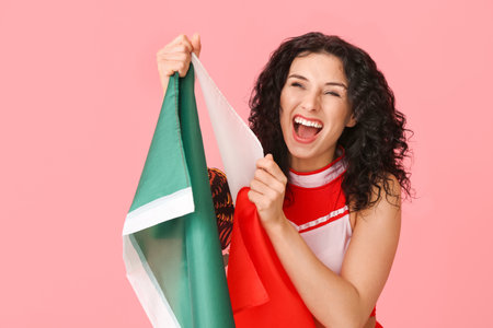 Emotional beautiful cheerleader with Mexican flag on color backgroundの写真素材