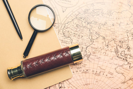 Old spyglass with magnifier and notebook on vintage world map