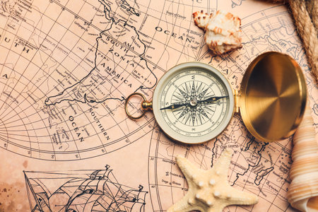 Old compass with sea shells on vintage world mapの写真素材