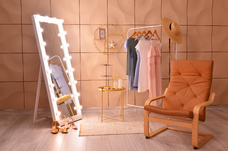Mirror, armchair and hanger with clothes in interior of living roomの写真素材
