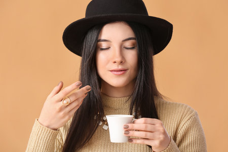 Beautiful young woman drinking coffee on color background, closeupの写真素材