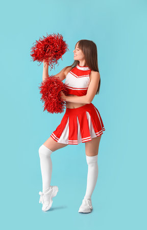 Beautiful young cheerleader on color background