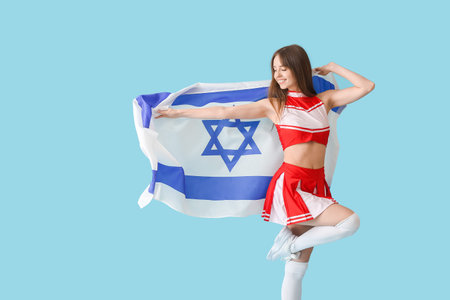 Beautiful young cheerleader with the flag of Israel on color backgroundの写真素材