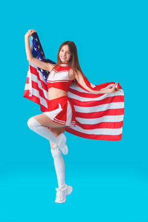 Beautiful young cheerleader with USA flag on color backgroundの写真素材