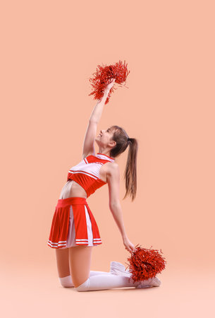 Beautiful young cheerleader on color backgroundの写真素材