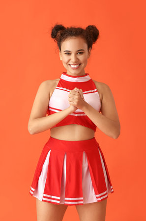 Beautiful young cheerleader on color background