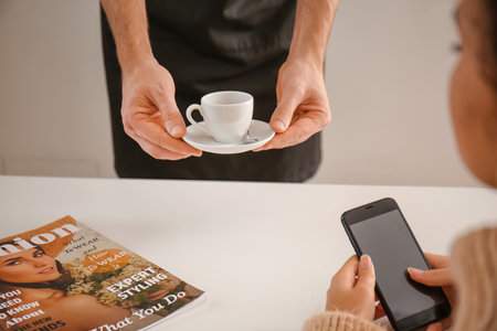 Barista bringing hot espresso for visitor in cafe