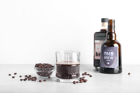 Composition with tasty cold brew and coffee beans on white background