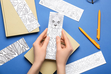 Female hands with cute bookmarks on color backgroundの写真素材