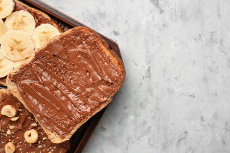 Wooden board of tasty toasts with hazelnut butter on light background, closeup