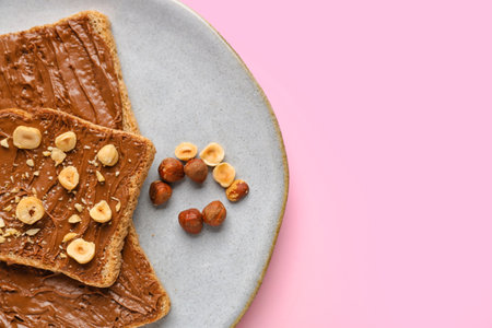 Plate of tasty toasts with hazelnut butter and nuts on pink background, closeupの写真素材