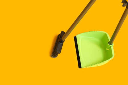 Cleaning broom with dustpan on yellow backgroundの写真素材