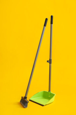 Cleaning broom with dustpan on yellow backgroundの写真素材