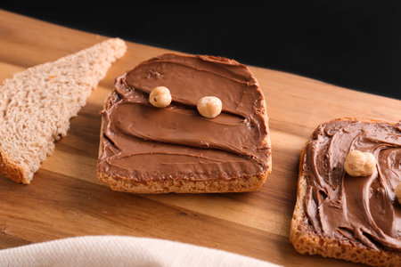Wooden board of toasts with hazelnut butter on dark background, closeupの写真素材