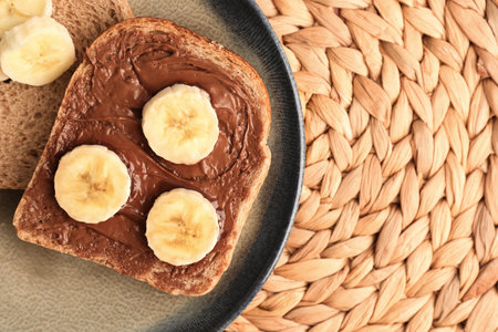 Plate of tasty toast with hazelnut butter and banana on wicker mat, closeupの写真素材