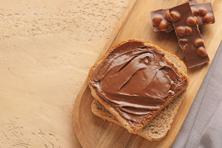 Wooden board of toasts with hazelnut butter and chocolate on color background, closeupの写真素材