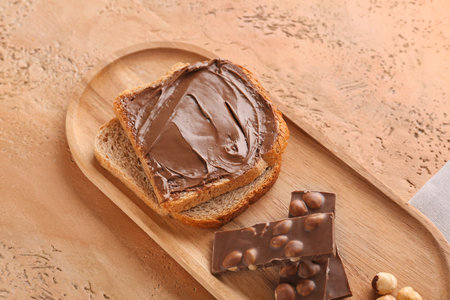 Wooden board of toasts with hazelnut butter and chocolate on color backgroundの写真素材
