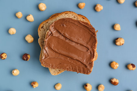 Tasty toasts with hazelnut butter and nuts on color background