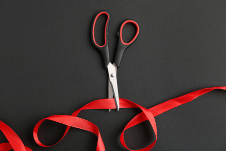 Scissors and red ribbon on dark backgroundの写真素材