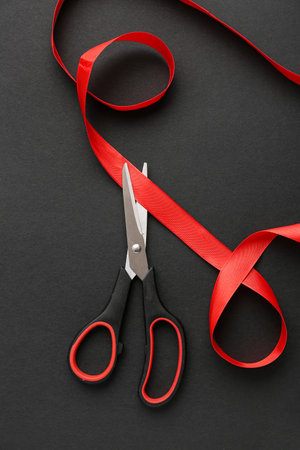 Scissors and red ribbon on dark backgroundの写真素材