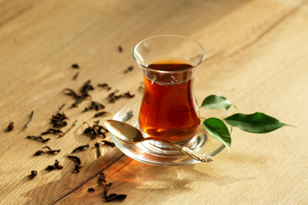 Glass cup of Turkish tea and dry leaves on wooden backgroundの写真素材