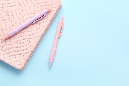 Pink notebook and pens on color backgroundの写真素材