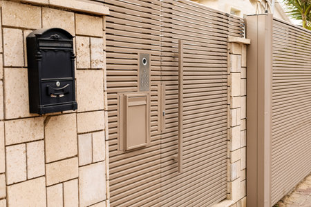 Modern fence with intercom and door outdoors