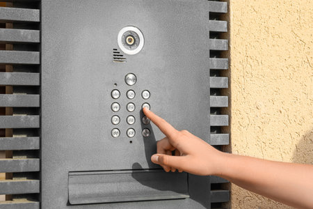 Little girl using modern intercom outdoors, closeup