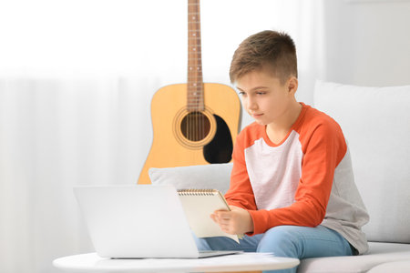 Little boy taking music lessons online at home